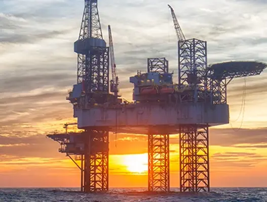 Offshoreoil platform in ocean with sunset in background