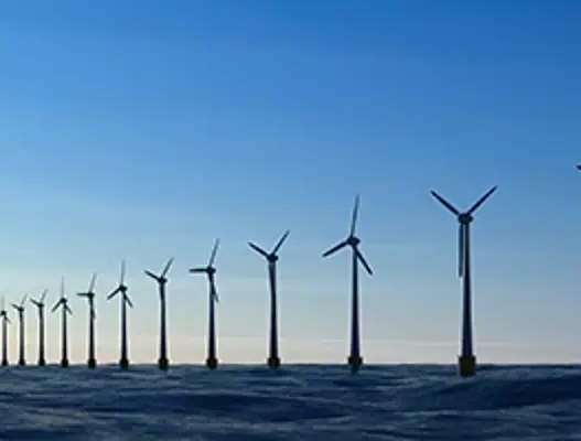 A line of offshore wind turbines with blue skies